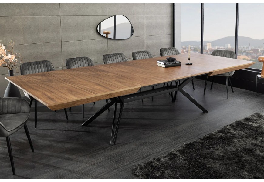 Moderný industriálny jedálenský stôl Gerant s obdĺžnikovou vrchnou doskou s možnosťou rozloženia z orechovej dyhy v naturálnej hnedej farbe s prirodzenou kresbou letokruhov s podstavou z kovu v matnom čiernom prevedení so štyrmi nohami