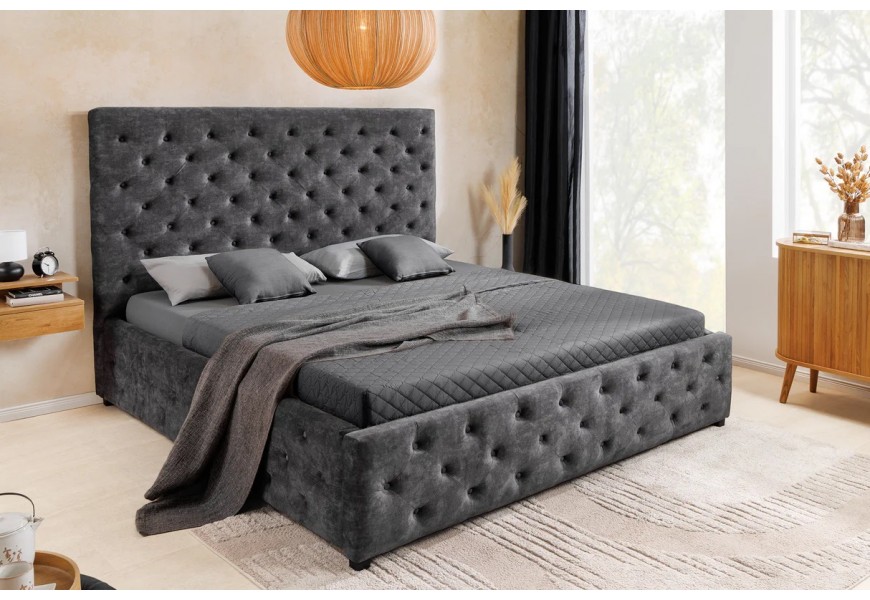 Dizajnová chesterfield manželská posteľ Kreon s obdĺžnikovým čelom a plnou základňou s úložným priestorom s nízkymi nožičkami s poťahom zo zamatu v tmavej sivej farbe s prešívaním s okrúhlymi gombíkmi