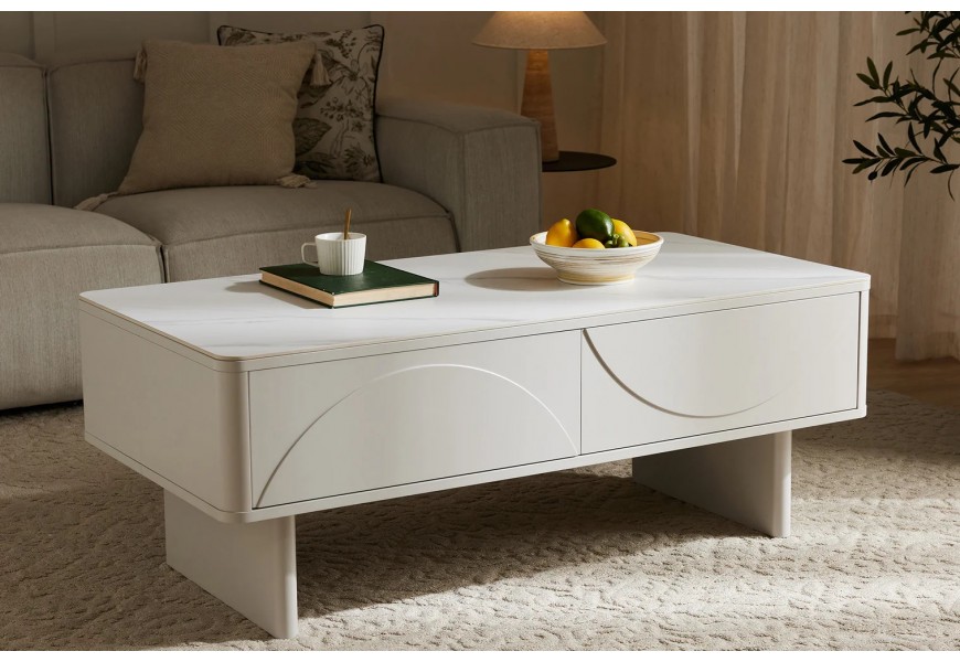 Dizajnový art deco konferenčný stolík Savonia s úložným priestorom s dvomi zásuvkami s geometrickým reliéfom a jednou policou na dvoch nohách a obdĺžnikovou keramickou doskou s dizajnom mramoru v bielej farbe