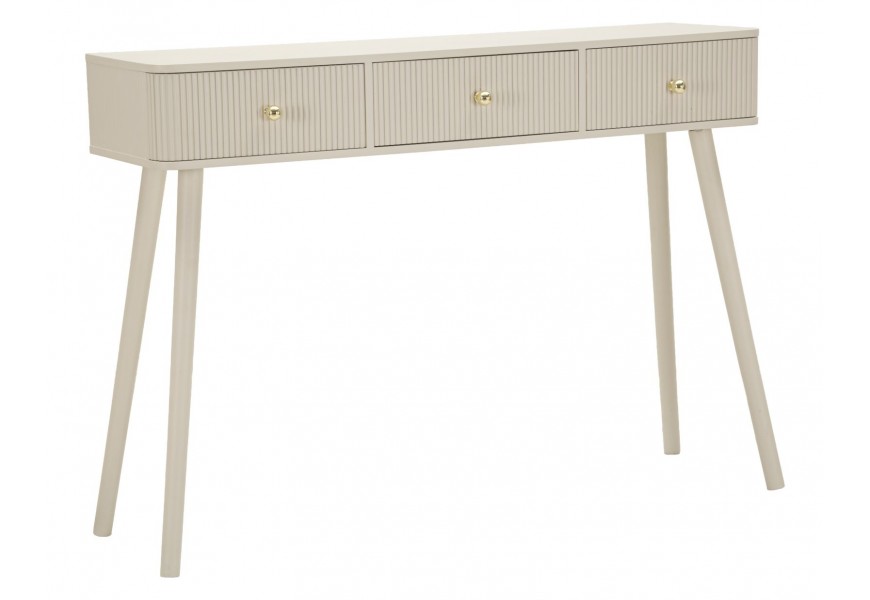 Art deco béžový konzolový stolík Shelly s obdĺžnikovou vrchnou doskou so zaoblenými prednými rohmi s tromi zásuvkami s okrúhlymi zlatými úchytkami s drážkovaným reliéfom na prednej a zadnej strane na šikmých nožičkách