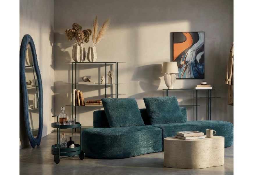 Moderná dizajnová zostava nábytku do obývačky v tmavej tyrkysovej farbe so sedačkou organického tvar a asymetrickým zrkadlom s knižnicou a konzolovým stolíkom s oválnymi policami s okrúhlym servírovacím stolíkom a konferenčným stolíkom z kameniny v sivej farbe atypického tvaru