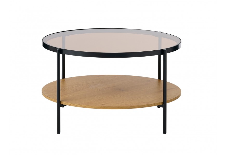Sklenený retro konferenčný stolík Sonny s okrúhlou vrchnou priehľadnou doskou s hnedým tónovaním s kovovým rámom v čiernej farbe a policou z melamínovej dyhy v svetlom hnedom dubovom prevedení