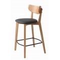 Moderná masívna barová stolička Vitro konštrukciou z dubového dreva so zaoblenou opierkou vo svetlej hnedej farbe s prírodnou kresbou letokruhov s čalúneným sedadlom s poťahom z ekokože v čiernej farbe s kovovou opierkou na nohy