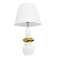 Dizajnová glamour stolná lampa Caillou s bielou akrylovou nohou so zaobleným geometrickým tvarom s kompozíciou na sebe uložených okruhliakov so zlatým detailom v strede s polohovateľným tienislom z bieleho textilu a rozšírenou spodnou stranou