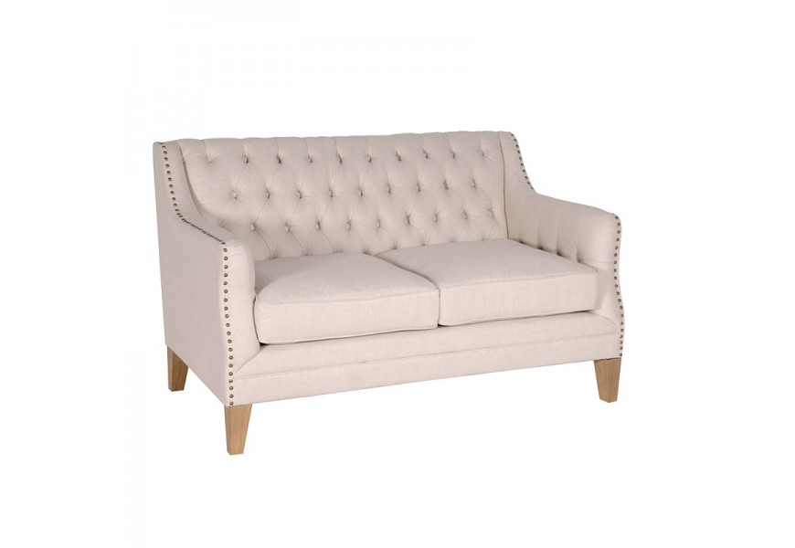 Štýlová chesterfield dvojsedačka Gresham v svetlom béžovom prevedení s kovovými cvokmi a masívnymi nožičkami