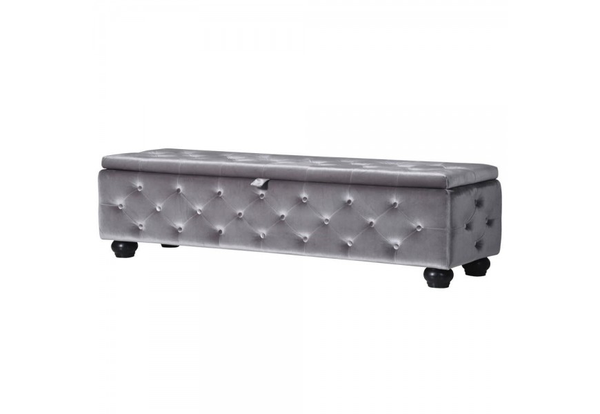 Štýlový taburet Alcala v Chesterfield štýle v sivej farbe zamatového poťahu doplnený čiernymi nohami a úložným priestorom