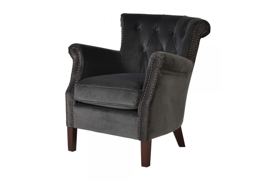 Štýlové kreslo Denvy v sivom zamatovom poťahu prešívaného v štýle Chesterfield a doplnené nohami z dreva v tmavo hnedom odtieni