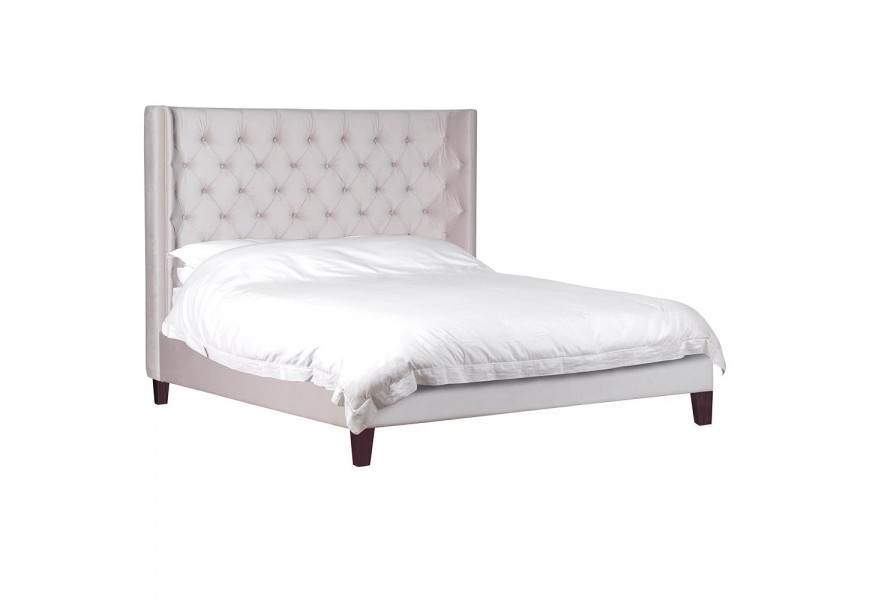 Štýlová Chesterfield posteľ Valerie s luxusným bledým zamatovým poťahom a nohami z borovicového dreva v tmavej farbe