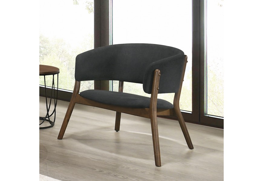 Moderné kreslo Nordica Nogal so zaoblenou chrbtovou opierkou s čalúnením v tmavosivej farbe a masívnymi hnedými nožičkami v severskom štýle