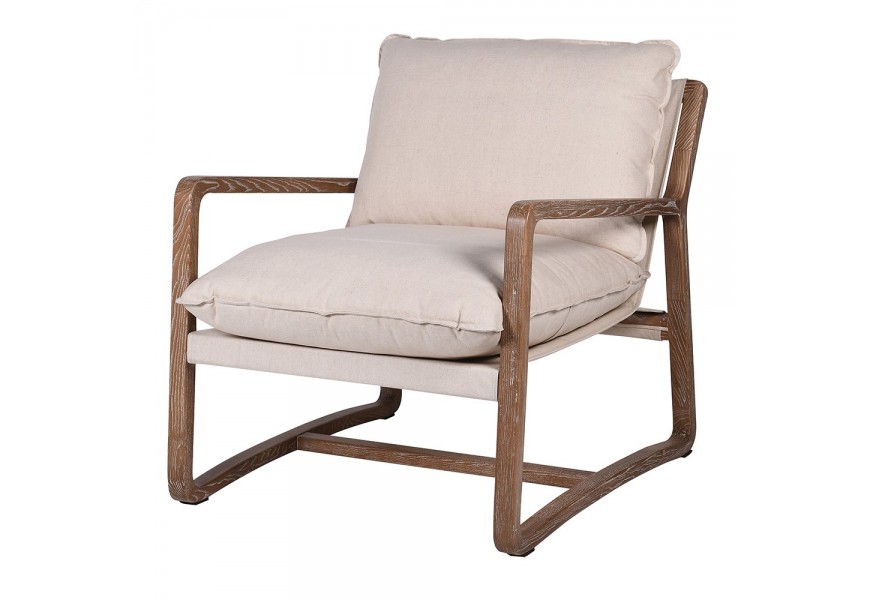 Masívne béžové kreslo Judith I s hnedými nohami a rukoväťami z jaseňového dreva s poťahom v odtieni šampanského vo vidieckom štý