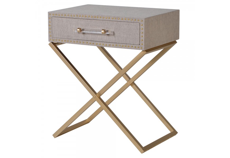 Štýlový moderný nočný stolík Stefan s kovovvou zlatou konštrukciou a prekríženými nožičkami s jednou čalúnenou zásuvkou v béžovo-ružovej farbe