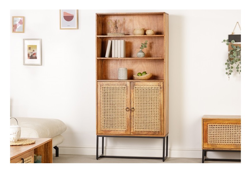 Masívna svetlohnedá knižnica Selina s čiernou kovovou podstavou a s ratanovým výpletom na dvierkach