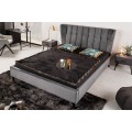 Moderná posteľ Alva s čiernymi nožičkami z dreva a sivým zamatovým čalúnením s nádychom retro štýlu