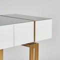 Art deco luxusný konzolový stolík Bynum biely so sklenenou doskou a kovovými nožičkami v zlatej farbe 120cm 