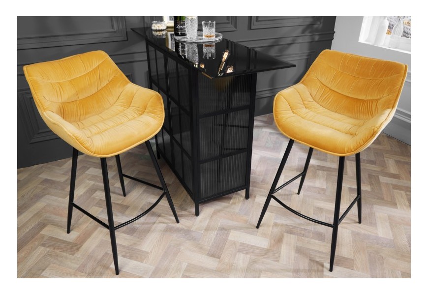 Moderná štýlová barová stolička Kotor žltej farby s poťahom zo zamatu a čiernou kovovou konštrukciou