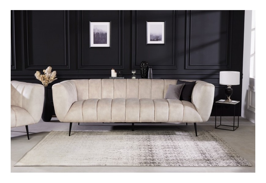 Art deco moderná zamatová sedačka Vermont v krémovej champagne farbe na čiernych kovových nožičkách s opierkami na ruky a štýlovým prešívaním