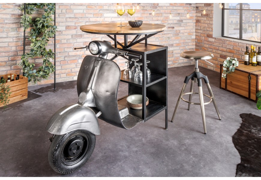 Dizajnový barový stôl Scooter s podstavou v tvare motorky v striebornej farbe s okrúhlou vrchnou doskou z mangového dreva a policami s čiernou kovovou konštrukciou