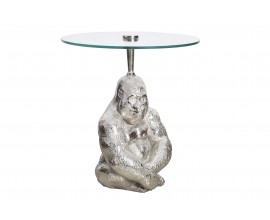 Okrúhly príručný stolík Wilde v art-deco štýle s figurálnou podstavou sediacej gorily v striebornej farbe a s vrchnou doskou z transparentného bezpečnostného skla