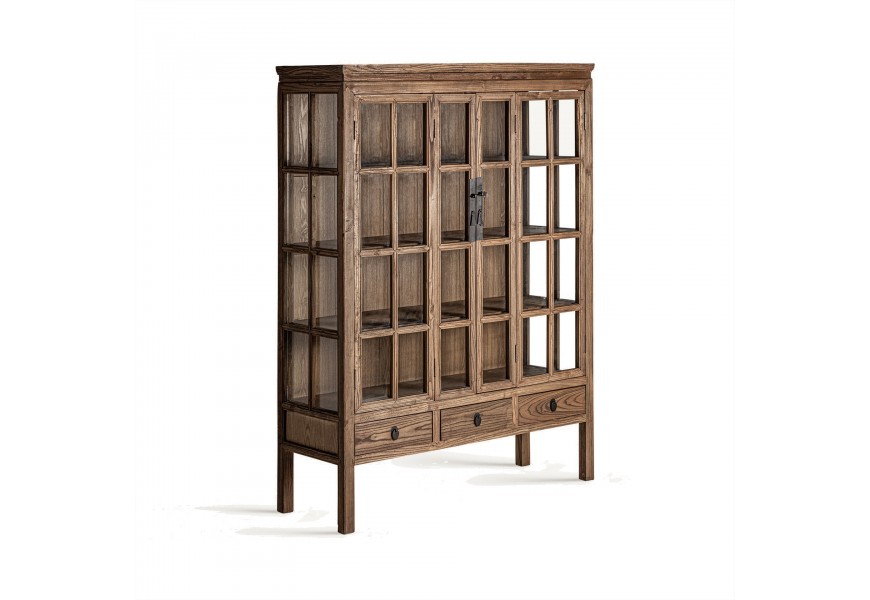 Luxusná vitrína Ethon z masívneho brestového dreva v svetlej hnedej farbe s prírodnou kresbou letokruhov na nožičkách v s tromi zásuvkami a s rozkladacími dvojitými dvierkami s tabuľovou sklenenou výplňou