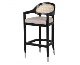 Dizajnová ratanová barová stolička Ryan s rámom z masívneho dreva v čiernej farbe s viedenským výpletom oválnej opierky v svetlej béžovej farbe a čalúnenou sedacou časťou so sivým poťahom s lesklým chrómovým ukončením nožičiek