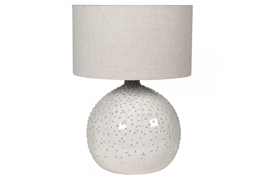Dizajnová moderná biela stolná lampa Espinilla s okrúhlym tienidlom z ľanovej textílie v sivej farbe a okrúhlou keramickou podstavou s asymetrickým reliéfnym vzorom v podobe bodiek