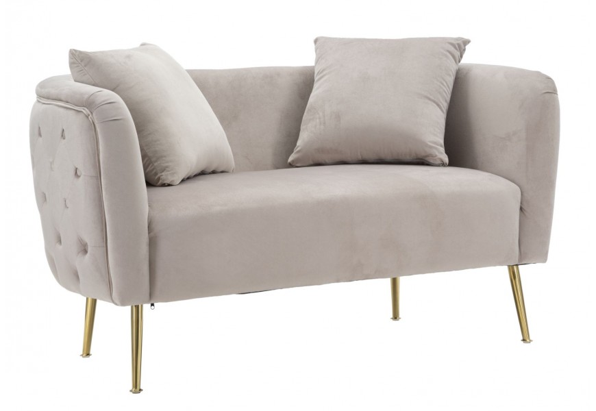 Glamour sedačka Zeran v obdĺžnikovom oblom tvare s poťahom v béžovej farbe so zamatovým leskom a prešívaným chrbtom a nožičkami v zlatej farbe z kovu