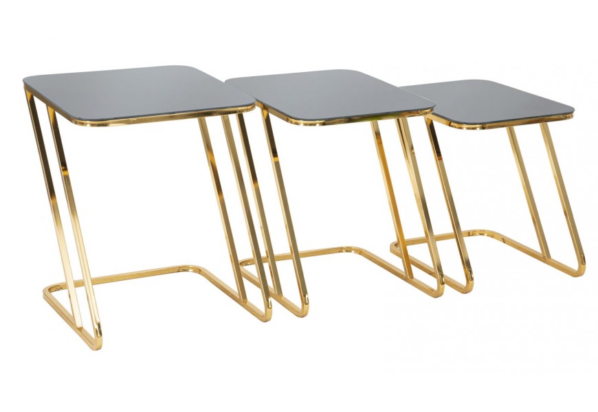 Art deco sada príručných stolíkov Aurialis s čiernymi sklenenými vrchnými doskami v elegantnom obdĺžnikovom tvare a lesklou zlatou kovovou konštrukciou v tvare Z