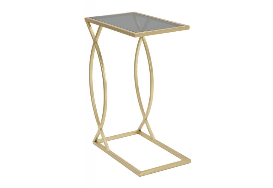 Glamour príručný stolík Magnus v zlatej farbe z kovu s vrchnou doskou zo skla v priehľadnej čiernej farbe s nohou s geometrickým vzorom