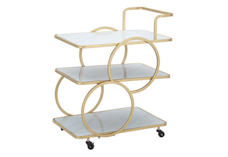 Dizajnový art deco kovový servírovací vozík Palais s geometrickou zlatou konštrukciou s troma obdĺžnikovými bielymi policami s bezpečnostným sklom s ergonomickou úchytkou so štyrmi nožičkami na kolieskach s brzdami