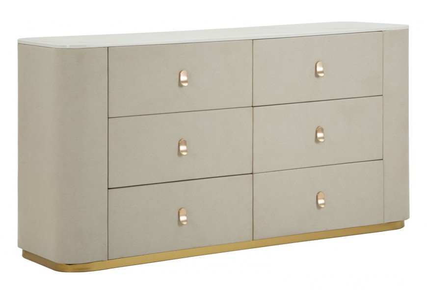 Art deco čalúnená komoda Glamia Tapisé obdĺžnikového tvaru so zaoblenými rohmi s textilným poťahom s výraznou štruktúrou v béžovej farbe so šiestimi zásuvkami umiestnenými v troch radoch s oválnymi úchytkami a kovovou podstavou v zlatej farbe