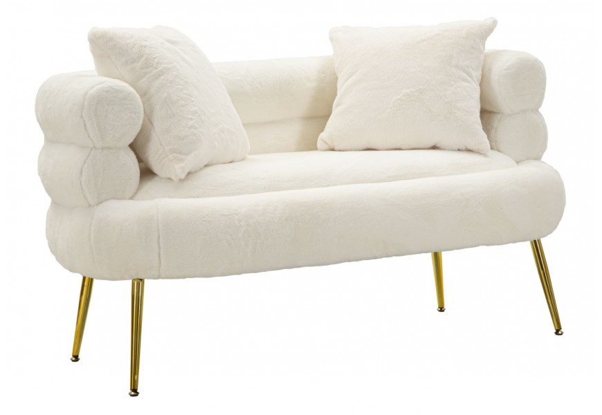 Dizajnová art deco sedačka Taglia s bielym poťahom z umelej kožušiny a dvomi vankúšmi s kovovými zošikmenými nohami v zlatej farbe s opierkou z troch valcovitých úrovní