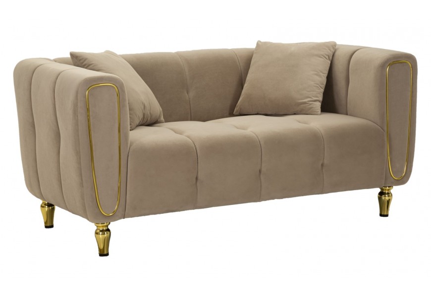 Dizajnový art deco dvojsedačka Celestia s mohutnými opierkami a dvomi vankúšmi so svetlohnedým prešívaným čalúnením a poťahom zo zamatu s nožičkami z kovu a detailom na prednej strane opierok v lesklom zlatom prevedení
