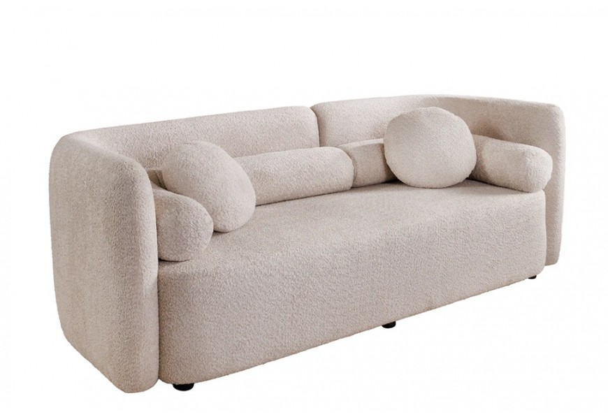 Art deco trojmiestna sedačka Jina v béžovej farbe s poťahom z bouclé látky s oblým asymetrickým operadlom a geometrickými okrúhlymi a valcovitými vankúšmi