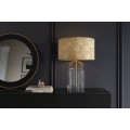 Glamour zlatá stolná lampa Gambier s okrúhlym tienidlom so vzorom palmových listov a priehľadnou sklenenou podstavou 55 cm