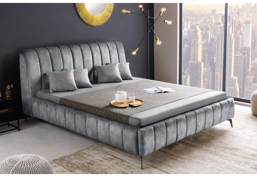 Moderná zamatová čalúnená posteľ Mai v sivom poťahu s vysokým čelom a vertikálnym prešívaním na čiernych tenkých kovových nožičkách