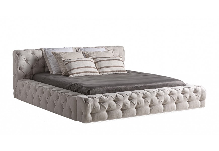 Luxusná chesterfield manželská posteľ Perivolos s hranatým čelom a plnou základňou s prešívaným čalúnením s hlbokými okrúhlymi gombíkmi a diamantovým vzorom s textilným poťahom v svetlej béžovej farbe