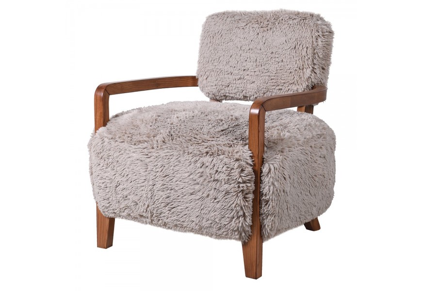 Luxusné dizajnové čalúnené kreslo Atzi s mohutnou sedacou časťou a obdĺžnikovou opierkou s poťahom z umelej kožušiny s dlhým vlasom v svetlej béžovej farbe so štyrmi nožičkami a opierkami na ruky z masívneho dreva v prírodnej hnedej farbe