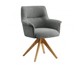 Moderné otočné čalúnené jedálenské kreslo Corvin s hranatou chrbtovou opierkou a vytočenými bočnými opierkami s poťahom v sivej farbe s plyšovej ženilkovej textílie s výrazným tkaním so štyrmi šikmými masívnymi nožičkami z dubového dreva v naturálnej svetlej hnedej farbe