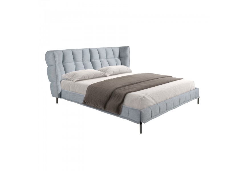 Luxusná dizajnová manželská posteľ Firmamento s mohutným čalúneným čelom s bočnicami s poťahom z textilu v melírovanej svetlej modrej farbe s prešívaním capitone so štvorcovým vzorom s nožičkami z nehrdzavejúcej ocele v tmavej farbe