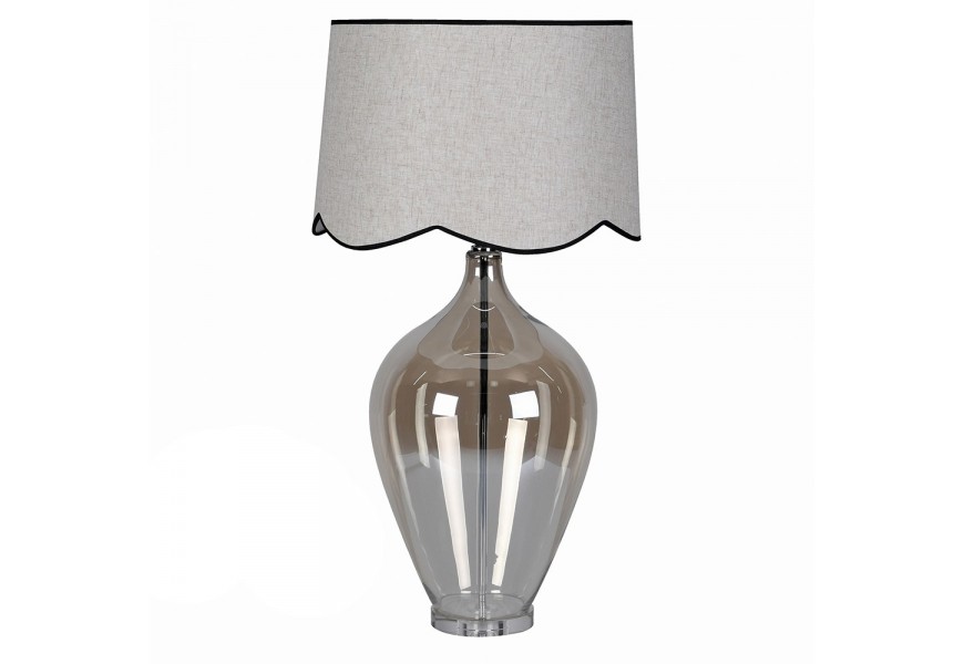 Moderná sklenená chrómová stolná lampa Silivano s priehľadnou lesklou nohou s hnedým tónovaním a kovovou konštrukciou so sivým okrúhlym textilným tienidlom s čiernym lemovaním a zvlnenou spodnou časťou