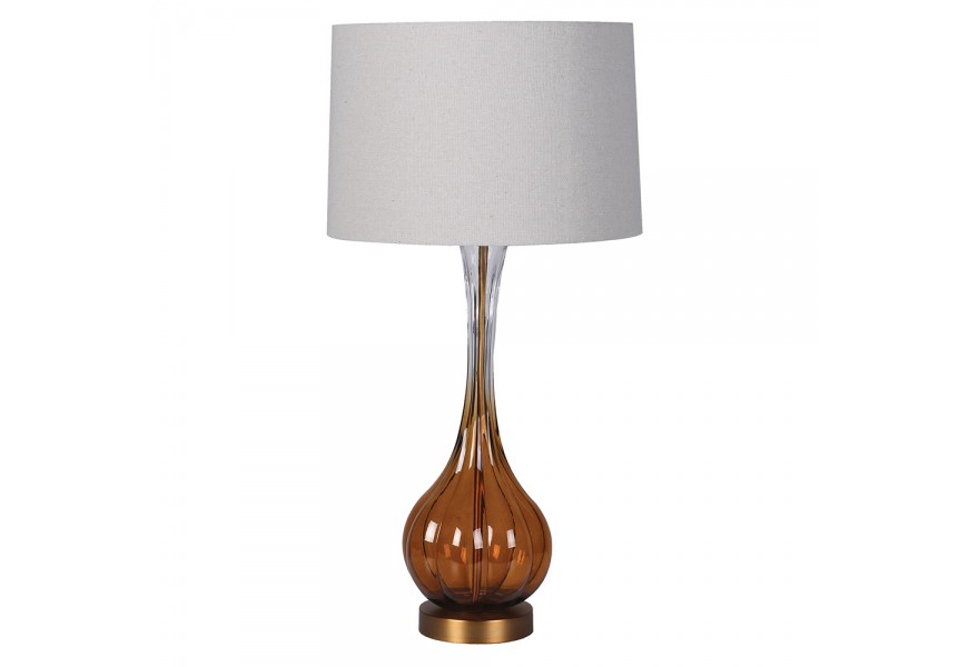 Glamour retro stolná lampa Antari s podstavou zo skla s hnedým tónovaním v spodnej časti s kovovou konštrukciou v zlatej farbe s okrúhlym tienidlom z ľanu v béžovej farbe