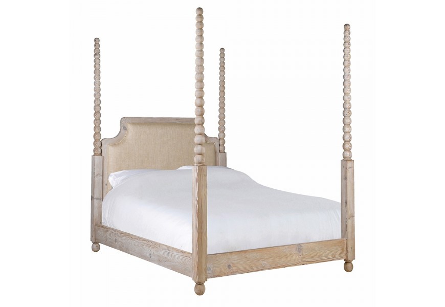 Luxusná vidiecka masívna manželská posteľ Boia s rámom z recyklovaného dreva v svetlej hnedej farbe na nízkych okrúhlych nožičkách so štyrmi vysokými stĺpikmi s vyrezávaným dizajnom guličiek a čelom s čalúnením v svetlej béžovej farbe