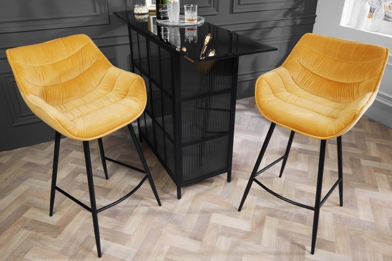 Estila Industriálna dizajnová barová stolička Kotor v žltom prevedení so zamatovým poťahom a čiernou kovovou konštrukciou 105cm